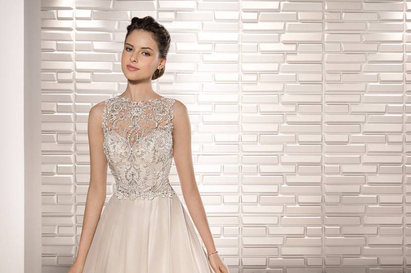 Style 679 <br>	Glamour and a little glitz make up this dreamy sleeveless ball gown with exquisite beading on the bodice, sheer Bateau neckline and dramatic illusion back with button closure.  The Tulle skirt flows into a Chapel length train.