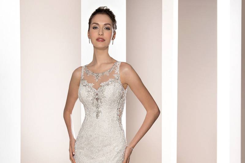 Style 665 <br>	This striking sleeveless, fit n flare gown with a sheer neckline accented with lace and crystal beading features lace over sheer side panels that continues into the dramatic back with button closure and Chapel train.