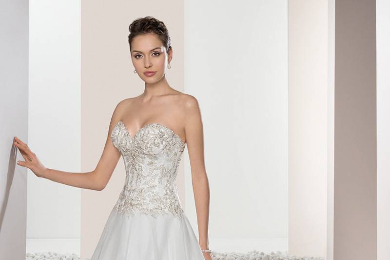 Style 662 <br>	This classic, strapless Ball gown features delicate lace cascading from the bodice into the skirt accented with jeweled trim on the waist.  The back is finished with a button closure and a Chapel length train.