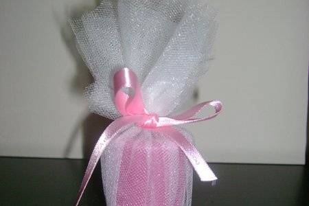 Votive candle wrapped in tulle and tied with a ribbon that has teh name of the bride and groom along with the date.