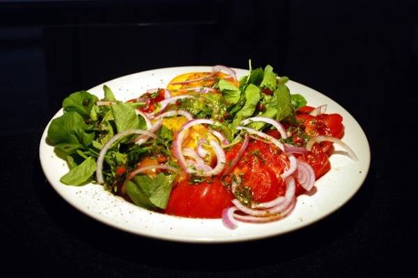 Heirloom tomatoes with fresh herbs, capers, red onion, and olive oil.