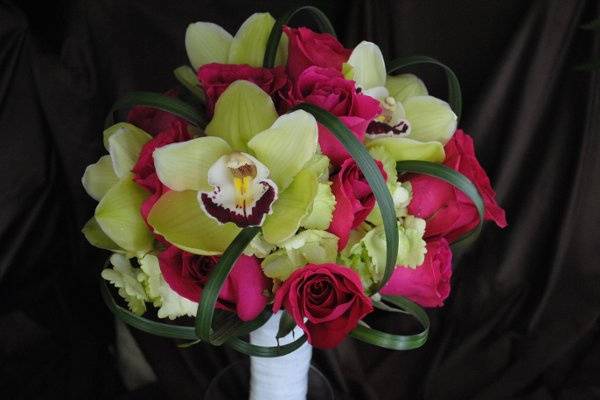 Pink roses, green hydrangea, green cymbidium orchids, and lily grass loops in a bridal bouquet