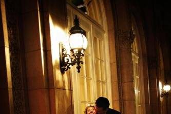 Bride and groom standing under light outside an old hotel.