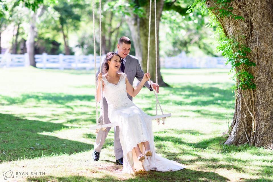 Groom pushing bride on swing