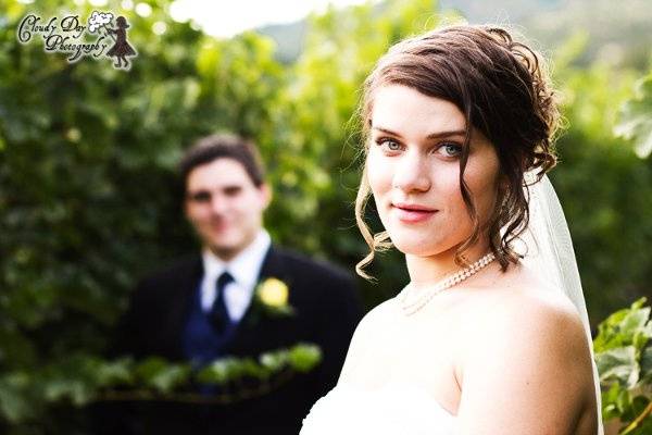 The bride is in the foreground, with the groom slightly blurred in the background, highlighting the vibrant white of the bride's dress.