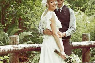 Retro style wedding photo of a newlywed couple on a bridge in the forest.
