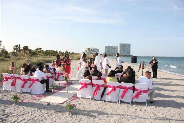 Bright pink on Tike torches, chair sashes, arch & petals in aisle