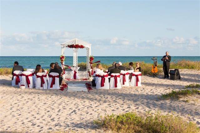 Red silk flowers on gazebo. Beach at Sea Watch restaurant. Violinist for ceremony.