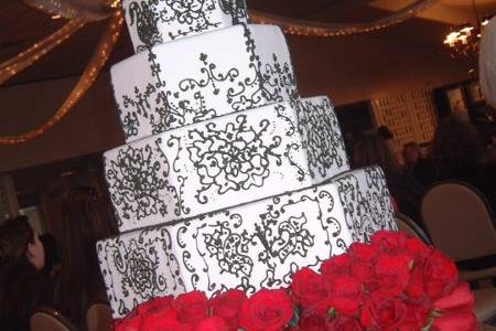 Fondant covered with dark chocolate details on a bed of fresh red roses.