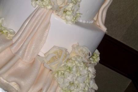 Fondant covered with fondant drapes and fresh flowers.
