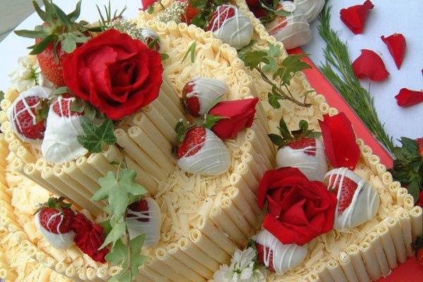 Cheesecake with white chocolate pencils, chocolate dipped strawberries and fresh flowers.