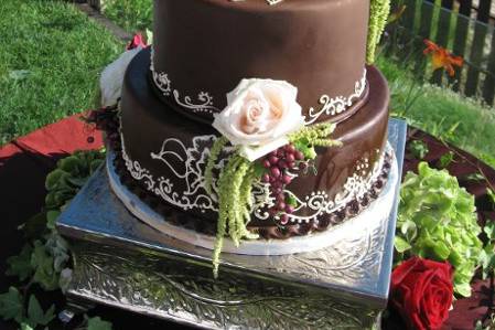 Covered in chocolate fondant with buttercream details, custom topper and fresh flowers.