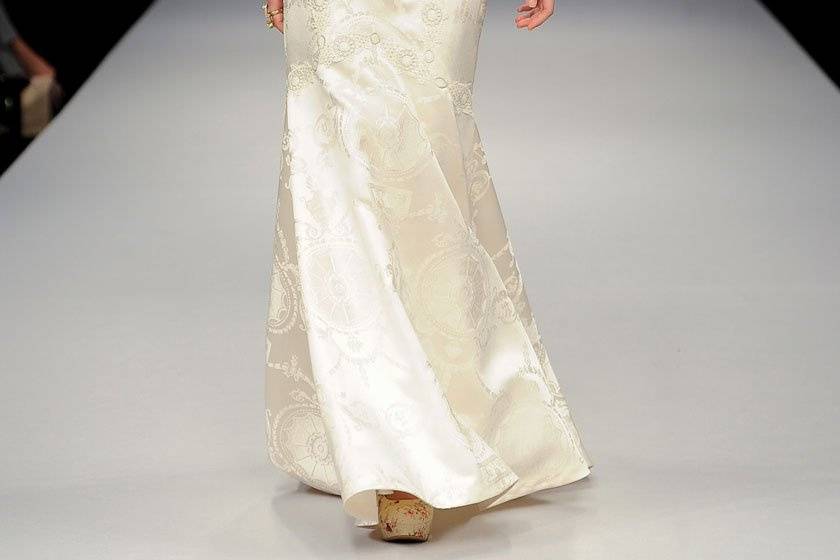 BRIGITTE <br>Silk white cap sleeved V-neck lace gown with silver guipure belt over full lace skirt lined in pearl silk.