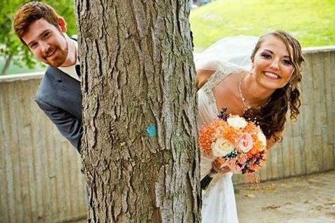 Couple peeking from behind tree