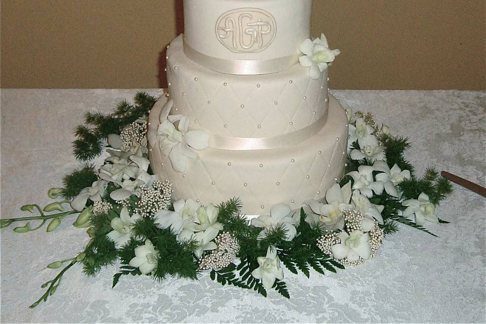 Elegant ivory wedding cake with quilted impression and pearls.  Monogram
