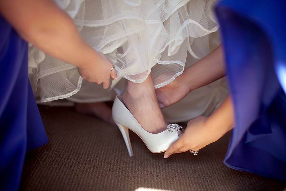 Bridesmaids helping bride with shoe