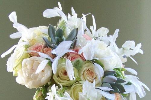 bridal bouquet with white sweetpeas, Polar Star roses, white peonies, white French tulips, green parrot tulips, bunny tail grass, succulents, scented geranium, Green Fashion roses, Star Blush spray roses, a linen and ivory lace stem wrap, and white eyelash feathers