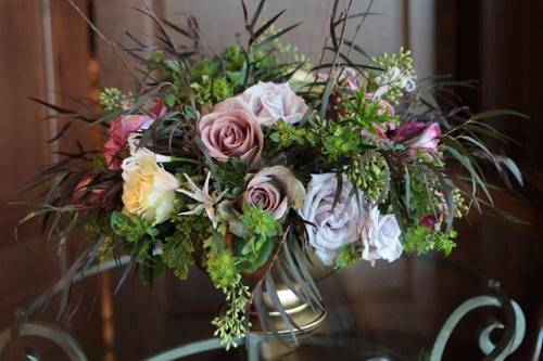 Garden style centerpiece with lavender hellebores, Amnesia roses, blackberries, Echeveria ‘Lucita’, seeded eucalyptus, scented geranium, and curly willow in a brown clay pot