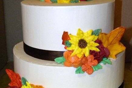 autumn themed flower cake with buttercream roses, blossoms and sunflowers with sugar paste fall leaves