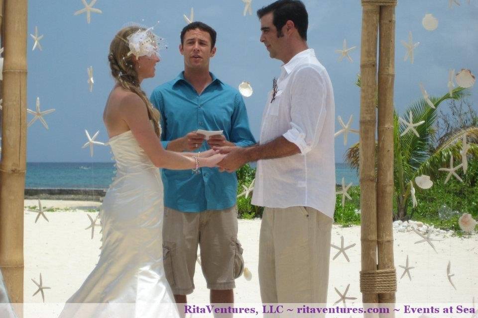 Beautiful view of the bride and groom underneath the bamboo canopy with hanging shells and starfish.