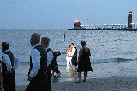 Rob and Tricia has their photo taken by photographer Jonathan Charpentier at sunset by the pier in Grand Haven, Michigan after their beach wedding officiated by Rev. Misty Urban. Photo copyright 2010 by GRWeddingOfficiant.com