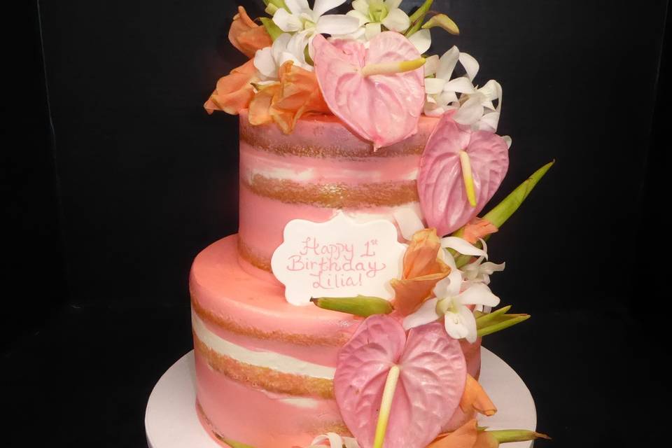 Semi naked pink buttercream finish with pink Anthurium, white orchids, and peach fresh flower cascade.