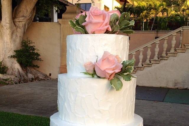 3 tier Stucco butter cream finish cake with fresh pink roses top and scattered.