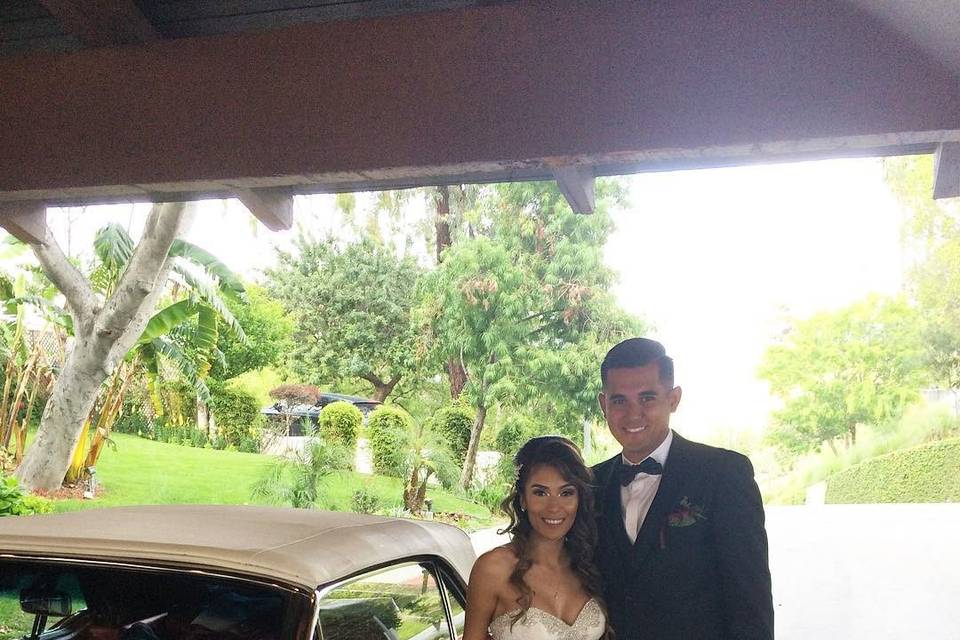 Bride and groom pose with vintage car