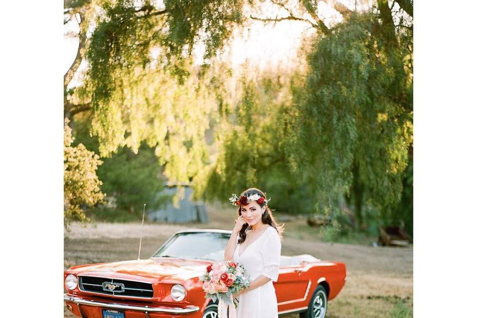 Bride posing with red convertible