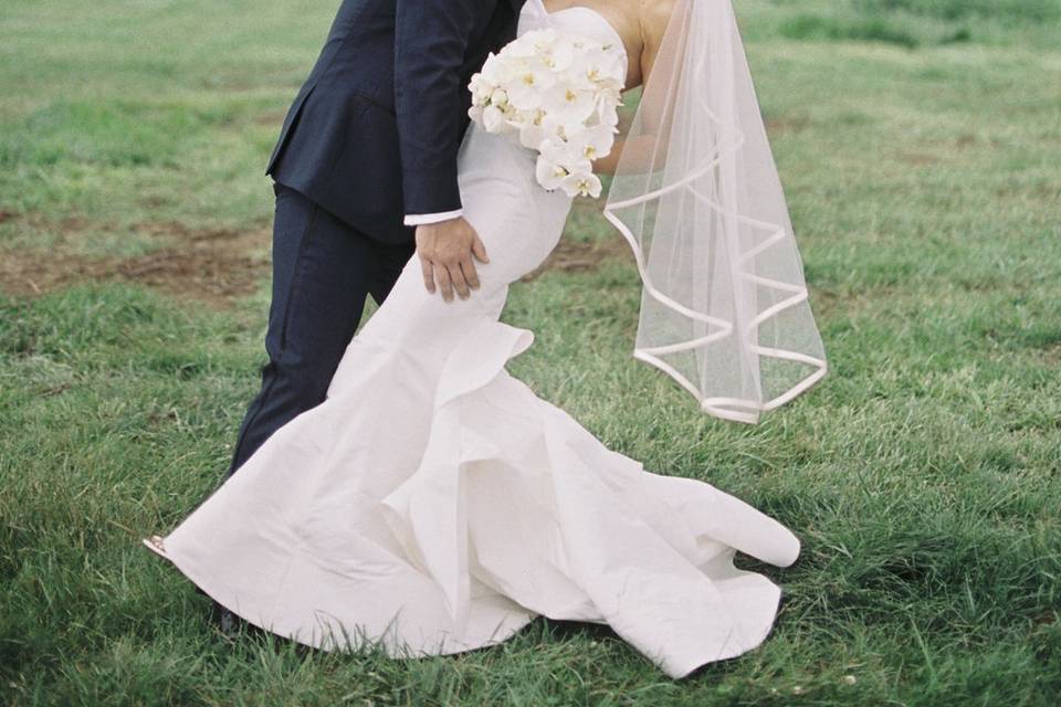 Newlyweds kissing in a field