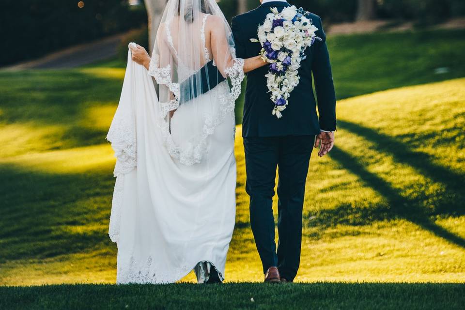 Newlywed couple walking towards a tree