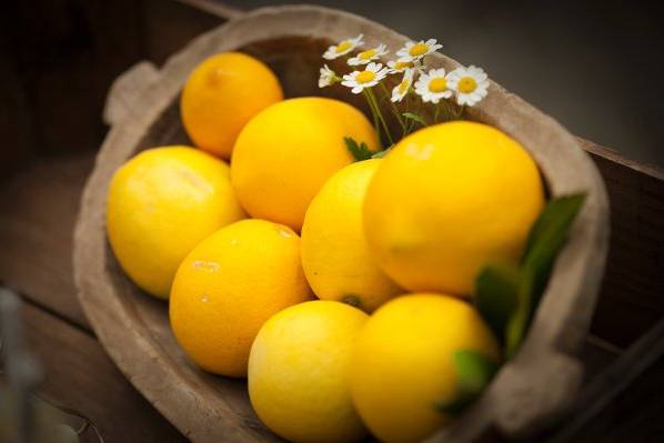 Vintage wooden bowl with organic lemons and chamomile.