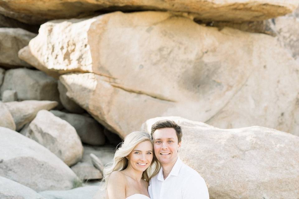 Couple pose beside boulders
