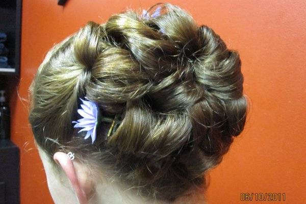 more twists than curls tightly pinned up with a small flower to match her formal  dress