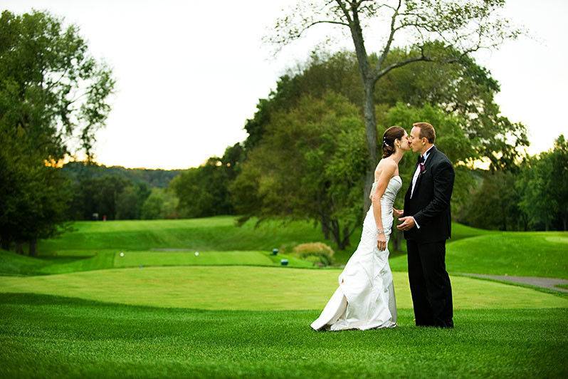 Bride and groom kissing on the course grounds