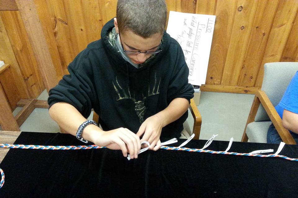 Handfasting ribbon of five different colors braided by hand by Be Wed By Fred. Ribbons of white being attached by Grooms' siblings.