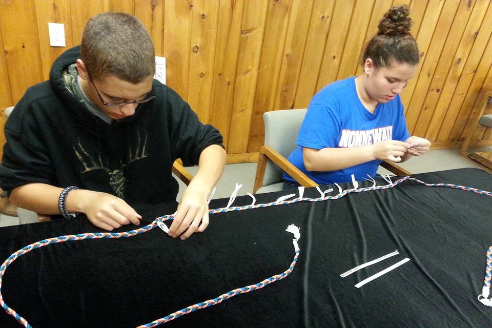 Handfasting ribbon of five different colors braided by hand by Be Wed By Fred. Ribbons of white being attached by Grooms' siblings.