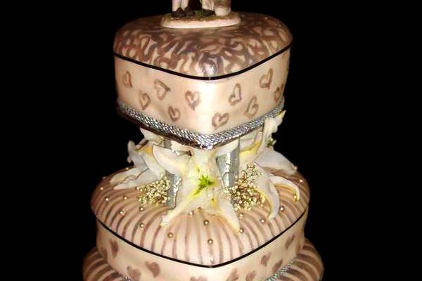 The layers of this old-fashioned wedding cake are heart shaped hat boxes. Done in modest, rustic colors, this cake features a 19th century topper - a schoolboy proposing to his first love.