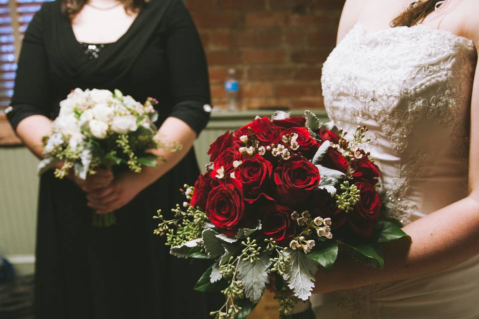 Bridal Bouquet created with red roses, dusty miller, seeded eucalyptus and wax flower.  Bridesmaids bouquet created with white roses, spray roses, lisianthus, dusty miller and wax flower.  Designed by Bill Hattel WH Designs Floral Events.