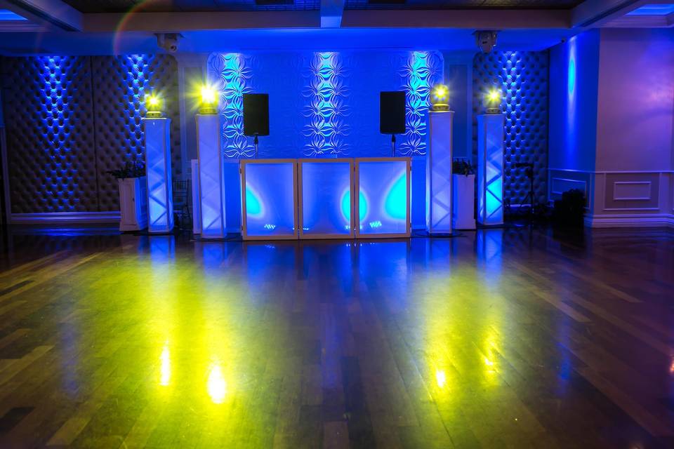 Illuminated DJ booth and two vertical towers and intelligent lighting