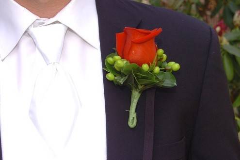 Red rose with green hypericum berries bout by Loeffler's Flowers