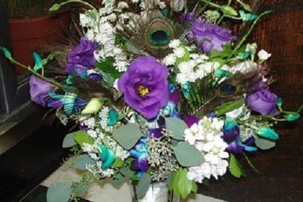 Purple lizzy, teal orchids, peacock feathers, stock and seeded eu wrapped stems bridal bouquet by Loeffler's Flowers