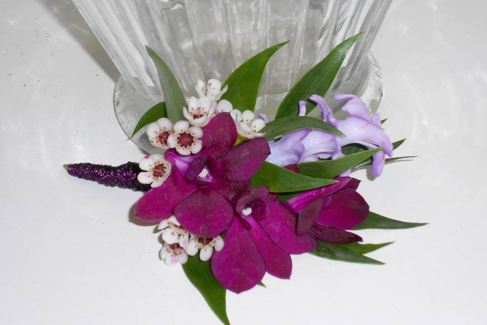 Boutonniere with dark purple dendrobium, hyacinth blooms and waxflower