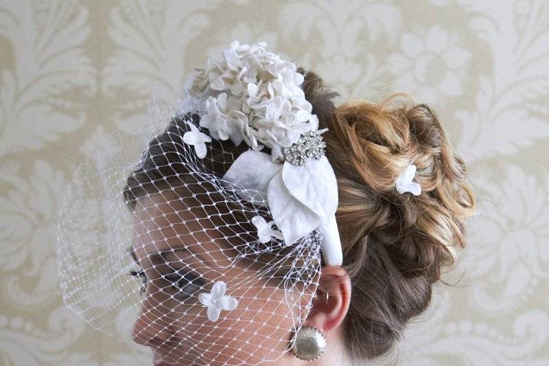 Capelli Fiore birdcage veil, dotted with tiny velvet flowers, on a headband with silk, velvet and organza flowers and feathers--tiny flowers on pins also in her hair.  Vintage rhinestone jewelry and mobe alabaster pearl earrings from The Something Old Collection.