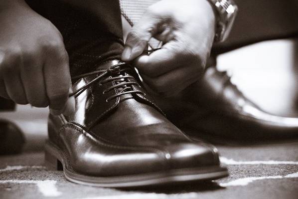 a groomsman ties his shoes