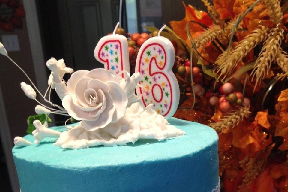 Two-tier tiffany blue cake with edible sugar lace, flowers, pearls, and bow.