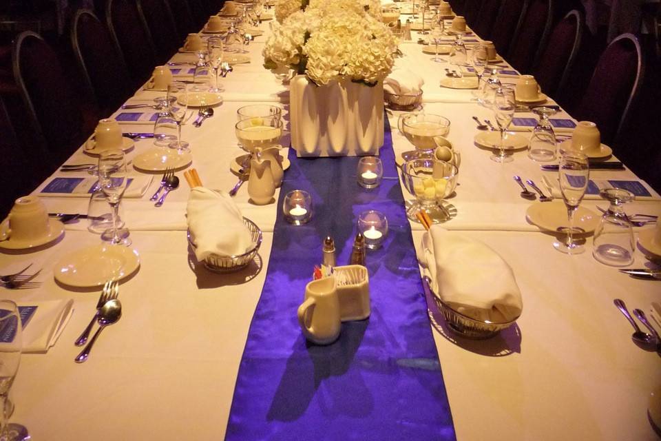 This large head table was the centerpiece to this entire space, and we framed the table spot in a perfectly trimmed pool of soft ivory light, highlighting the amazing florals and purple linen accents.  Uplighting and spotlit bead 