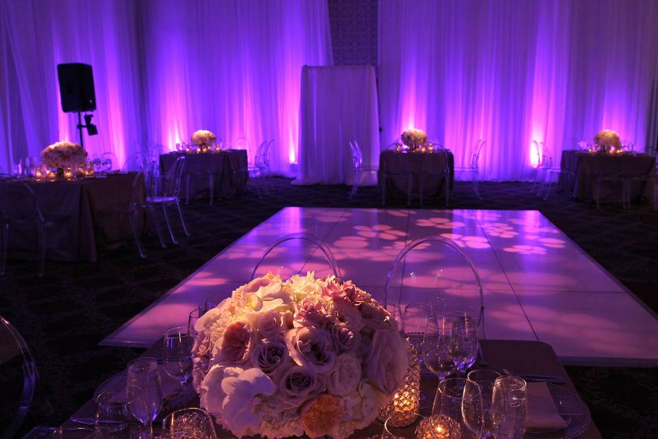 Rich purple uplit sheer drapes framed this small reception, which also featured floral projections on the dancefloor.