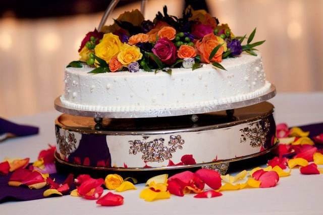 This is an ice cream cake! decorated with spray roses in pink, yellow, orange and a touch of green hypericum berries.