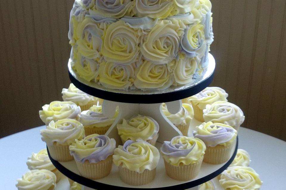 2 tier round wedding cake with cupcakes to match.  Buttercream icing with lavender and white swirl roses.